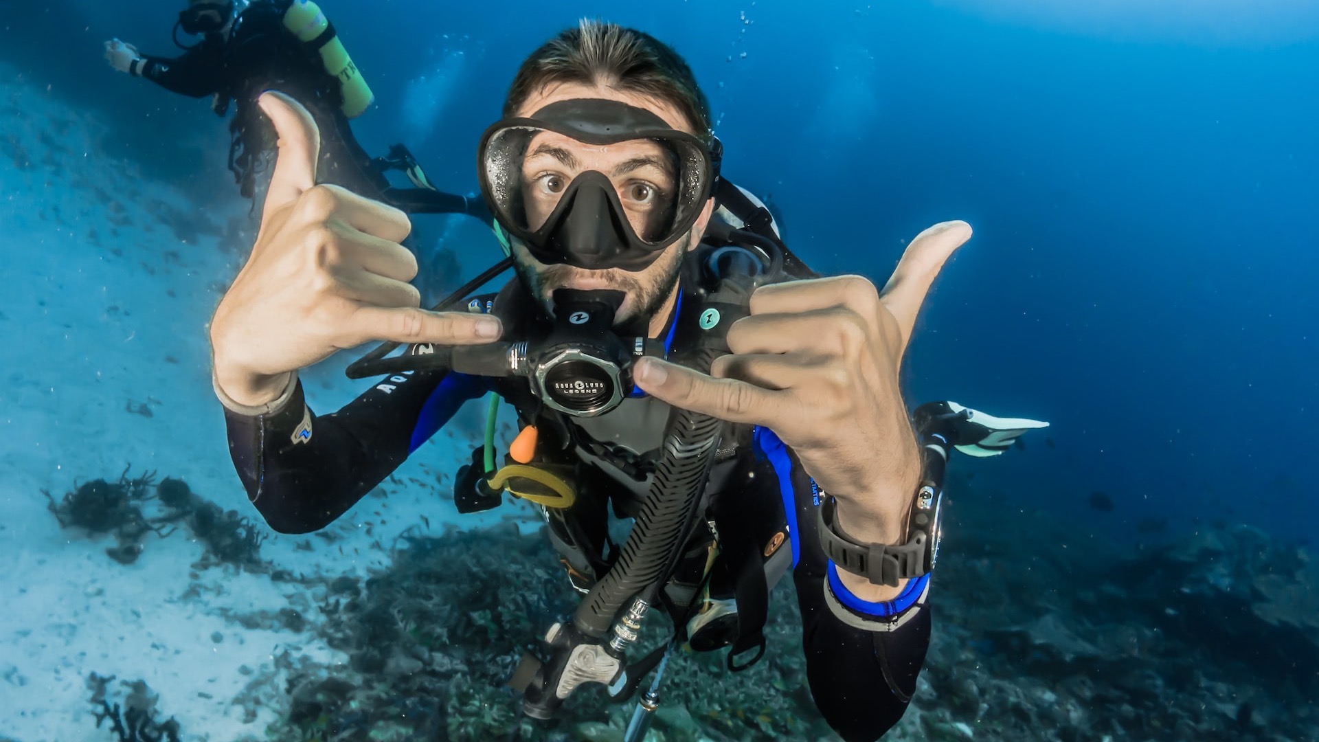 man underwater making hand signs